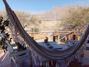 a hammock on a deck with a table at La Arenosa in Cafayate