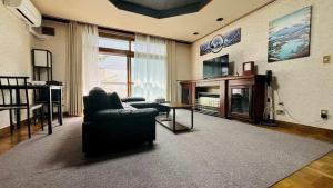 a living room with a couch and a chair and a television at SecondHouse Green in Otaru