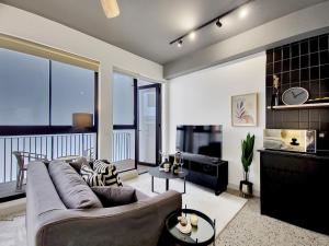 a living room with a large couch and a balcony at Brand new, luxury, wifi, pool with 24hr security in Cape Town