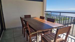 a wooden table and chairs with a view of the ocean at Métisse M&J location voiture sur demande in Saint-Paul