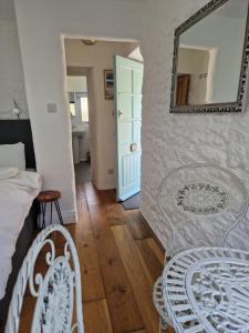 a bedroom with a mirror and a bed and a chair at Primrose Cottage peaceful room and private garden in Helston