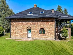 a brick house with a roof on a lawn at Willa Mortęgi in Lubawa