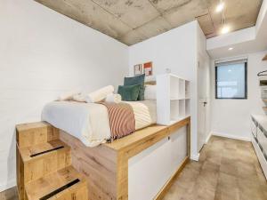1 dormitorio con 1 cama en una plataforma de madera en Stylish studio with Pool Access, en Ciudad del Cabo 11 fotos más