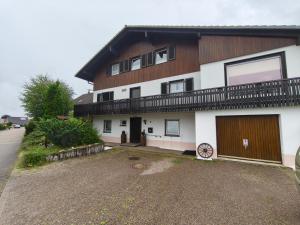 a large white house with a balcony and a driveway at Schwarzwald Apartments III in Lenzkirch