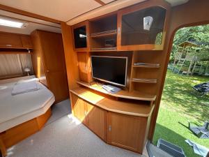 a bedroom with a tv and a bed in a rv at Lazy Days Caravan in Berlin +8 photos