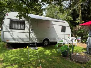 a white caravan parked in a yard with a table at Lazy Days Caravan in Berlin