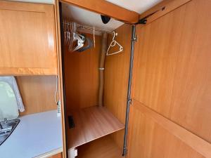 a cupboard with shoes and hangers in an rv at Lazy Days Caravan in Berlin