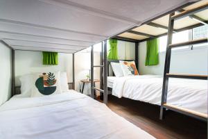 two bunk beds in a room with green curtains at Friend House BKK in Bangkok