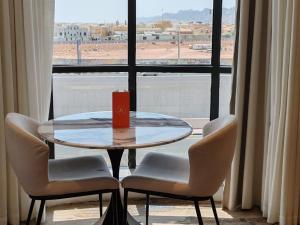 a table with two chairs and a red candle on it in a window at Ayas Hail Hotel - فندق أياس حائل in Hail