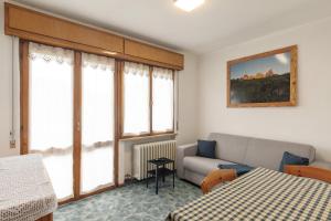 a room with a bed and a couch and windows at Dolomitihouse AUNER in Fiera di Primiero