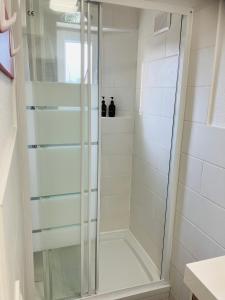 una doccia con una porta in vetro in un bagno di Maison avec 2 chambres et jardin a Montfort-le-Gesnois