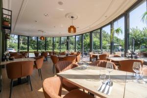 a restaurant with tables and chairs and windows at Fletcher Hotel-Restaurant De Kempen in Reusel