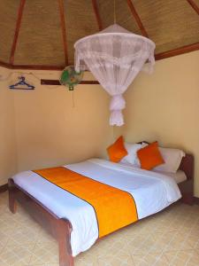 a bedroom with a bed with white sheets and orange pillows at New Court View Hotel in Masindi
