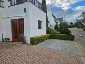 a white house with a red door and a brick driveway at Protea Rus in Wellington