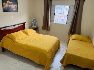 a bedroom with two beds with yellow covers and a window at Chácara Barone - Chácara em SerraNegra in Serra Negra +19 photos
