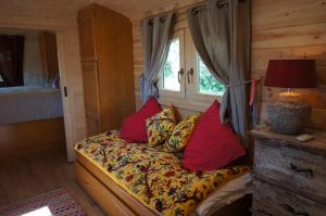 ein Schlafzimmer mit einem Bett mit Kissen und einem Fenster in der Unterkunft Le Pont Rouge Roulotte in Sylvéréal