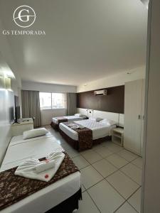 a hotel room with three beds and a tv at Hotel suits Le jardin in Caldas Novas