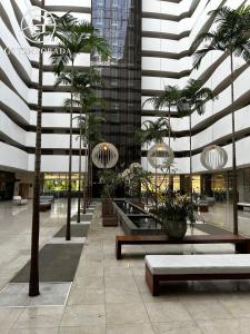 a lobby with palm trees and benches in a building at Hotel suits Le jardin in Caldas Novas