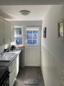 a white kitchen with a sink and a window at Tea Lane Cottage in Carnlough