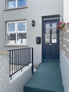 a blue door on a white house with a stairs at Tea Lane Cottage in Carnlough