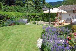 a garden with purple flowers and an umbrella at Villa Montelago in Rottach-Egern