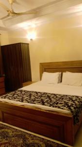 a bedroom with a large bed with a wooden headboard at Saint Rose Guest House in Islamabad