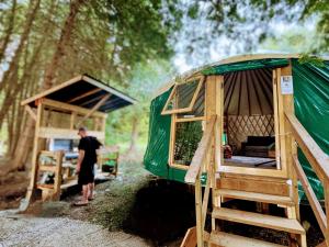 a woman standing in front of a green tent at Waterfront CedarGrove Yurt-Glamp in Red Bay