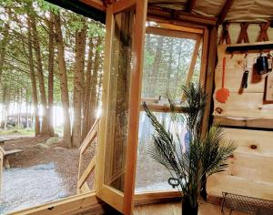 a window in a cabin with a view of a forest at Waterfront CedarGrove Yurt-Glamp in Red Bay +22 photos
