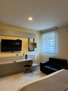 a hotel room with a couch and a desk and a tv at Mirago Hotel in Yumbo +24 photos
