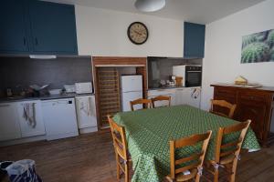 eine Küche mit einem Tisch mit Stühlen und einer Uhr an der Wand in der Unterkunft La maison du Thoré in Saint-Amans-Valtoret