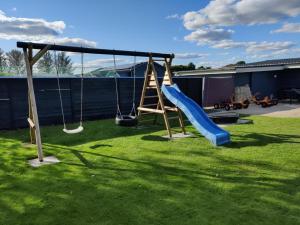 a playground with two swings on a lawn at Landstedet Billund in Billund