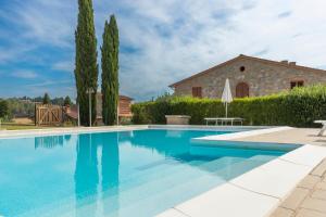 a swimming pool in front of a house with trees at I Sette Ulivi in Laiatico