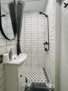 a white bathroom with a sink and a shower at Central Park Apartment in Šiauliai