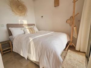 une chambre avec un lit avec une couette blanche dans l'établissement Authentic Taghazout, à Taghazout