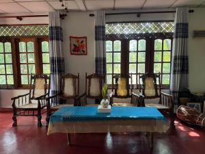 a dining room with a table and chairs and windows at Juno Homestay in Mulatiyana