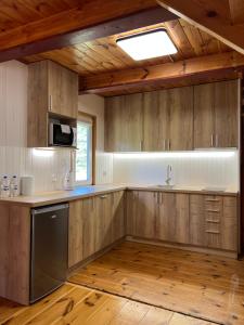 a kitchen with wooden cabinets and a sink and a window at Domki Pod Lasem in Macharce
