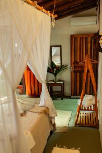 een slaapkamer met een bed met witte gordijnen bij Chalé Refúgio da Mata em Trancoso in Trancoso