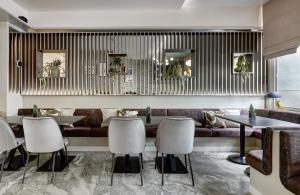 a restaurant with a couch and tables and chairs at Leonardo Hotel Muenchen City West in Munich