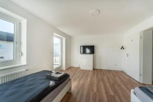 una camera da letto bianca con un letto e una TV di Monteur- & Gästewohnung mit Küche, WLAN & Parkplatz - SCH04 a Schramberg