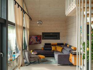 a living room with a gray couch and yellow pillows at SEOVILLAGE Resort & Spa in Ķeipene