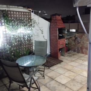 a patio with a glass table and chairs and a brick oven at Cobertura posto 5 in Rio de Janeiro