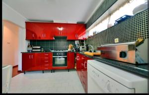 a red kitchen with red cabinets and a sink at Casa da Ruben Lisboa in Lisbon