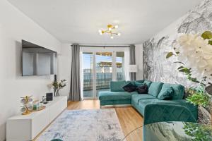 a living room with a green couch and a tv at Balcony Apartment I Direct connection to the Airport in 15 Min in Vienna