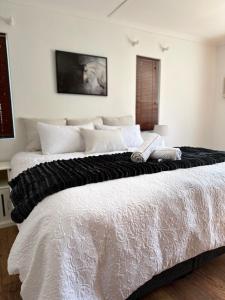 a large bed with a black and white blanket on it at Mario & Luiza's Place - Cozy Stay with Pool & Braai in Worcester