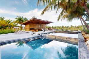 a swimming pool in front of a house with palm trees at Seabird Villa 23 in Placencia Village
