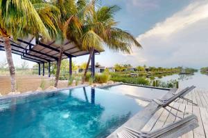 a swimming pool with a deck and palm trees at Seabird Villa 23 in Placencia Village