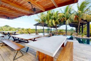 a patio with tables and benches and a pool at Seabird Villa 23 in Placencia Village