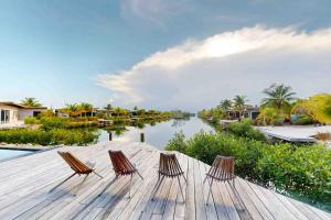 three chairs sitting on a wooden deck next to a river at Seabird Villa 23 in Placencia Village