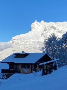 a snow covered house in front of a mountain at Chalet LA TOUPINE centre St Gervais in Saint-Gervais-les-Bains