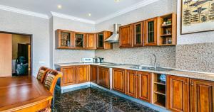 eine Küche mit Holzschränken, einer Spüle und einem Tisch in der Unterkunft Okean Apartment in Nizami str in Baku